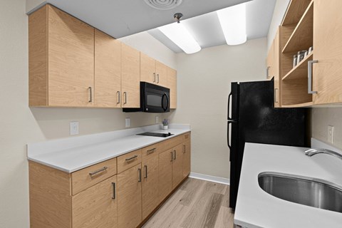 A kitchen with wooden cabinets and a black refrigerator.